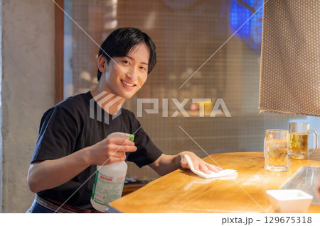 居酒屋　飲み物をお客さんに提供する女性スタッフ 129675318