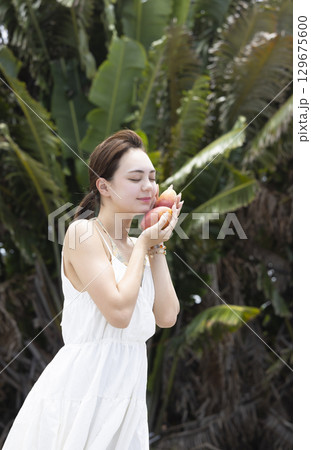 マンゴーを持つ綺麗な女性 129675600