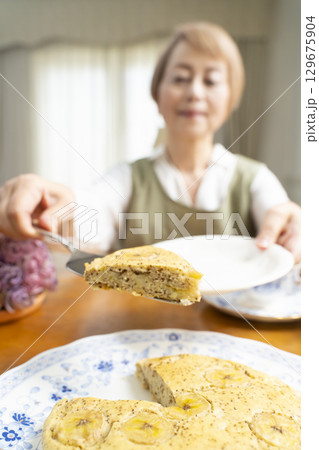 ケーキを焼いて紅茶を入れ自分時間を楽しむシニア女性 129675904