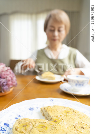ケーキを焼いて紅茶を入れ自分時間を楽しむシニア女性 129675905