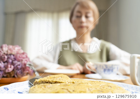 ケーキを焼いて紅茶を入れ自分時間を楽しむシニア女性 129675910