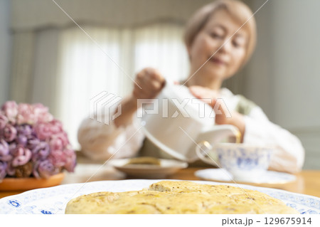 ケーキを焼いて紅茶を入れ自分時間を楽しむシニア女性 ケーキを焼いて紅茶を入れ自分時間を楽しむシニア女性 129675914