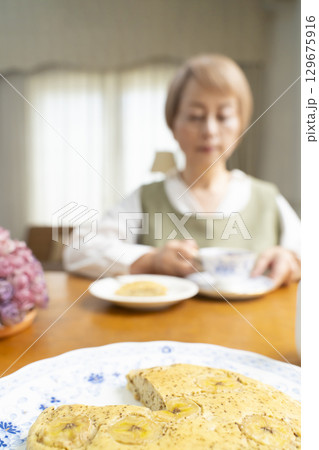 ケーキを焼いて紅茶を入れ自分時間を楽しむシニア女性 ケーキを焼いて紅茶を入れ自分時間を楽しむシニア女性 129675916