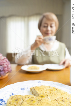 ケーキを焼いて紅茶を入れ自分時間を楽しむシニア女性 129675917