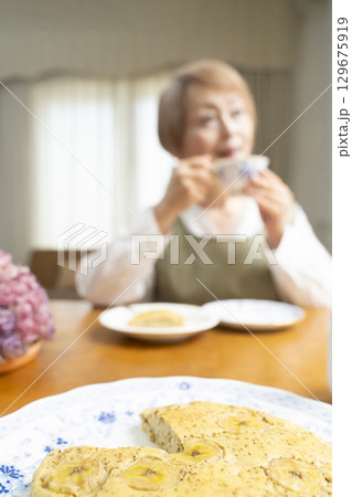 ケーキを焼いて紅茶を入れ自分時間を楽しむシニア女性 129675919