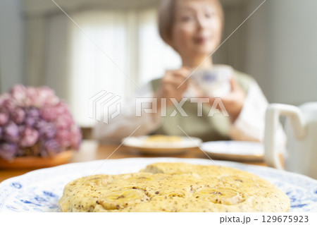 ケーキを焼いて紅茶を入れ自分時間を楽しむシニア女性 ケーキを焼いて紅茶を入れ自分時間を楽しむシニア女性 129675923