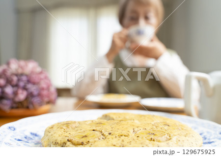 ケーキを焼いて紅茶を入れ自分時間を楽しむシニア女性 129675925