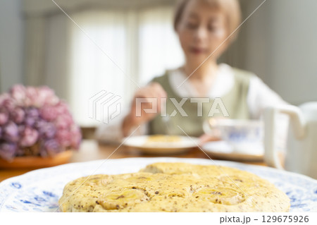 ケーキを焼いて紅茶を入れ自分時間を楽しむシニア女性 ケーキを焼いて紅茶を入れ自分時間を楽しむシニア女性 129675926