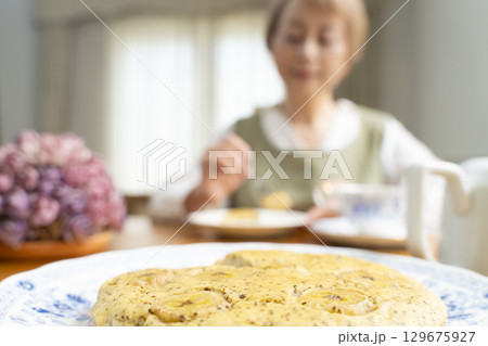 ケーキを焼いて紅茶を入れ自分時間を楽しむシニア女性 129675927