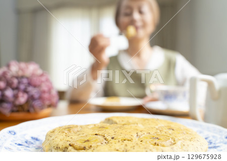 ケーキを焼いて紅茶を入れ自分時間を楽しむシニア女性 129675928