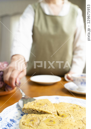 ケーキを焼いて紅茶を入れ自分時間を楽しむシニア女性 顔無し ケーキを焼いて紅茶を入れ自分時間を楽しむシニア女性 顔無し 129675953