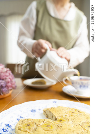 ケーキを焼いて紅茶を入れ自分時間を楽しむシニア女性 顔無し ケーキを焼いて紅茶を入れ自分時間を楽しむシニア女性 顔無し 129675957