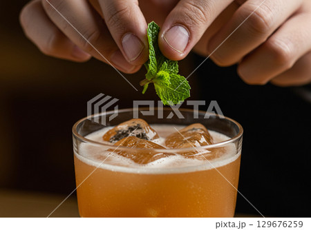 Bartender Adding Fresh Mint to Refreshing Cocktail 129676259