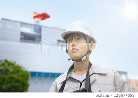 工事現場でタブレットを見る作業服の若いビジネスマン 工事現場でタブレットを見る作業服の若いビジネスマン 129677059