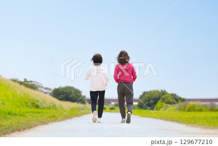 スポーツウェアでウォーキングするミドル女性2人の後ろ姿 129677210