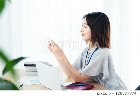 オフィスでスマホを見るビジネスウーマン オフィスでスマホを見るビジネスウーマン 129677774