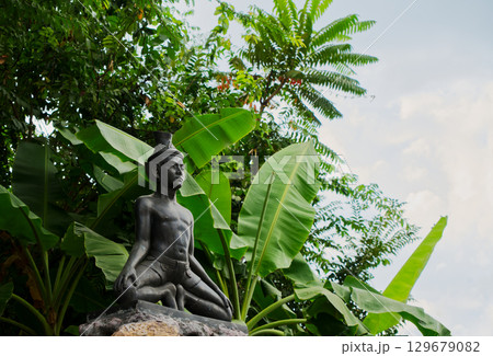 Statue of a hermit stretching under the shade of a tree inside Wat Pho or Pho Temple of Bangkok, Thailand. One of many statues of a hermit stretching in the area of the Wat Phra Chetuphon or Wat Pho  129679082