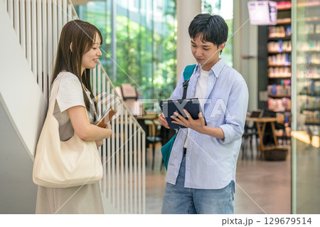 　校内でタブレットを見る男女大学生 129679514