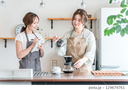 コーヒー教室・珈琲スクールでコーヒーの淹れ方を教える講師の女性と生徒の女性 コーヒー教室・珈琲スクールでコーヒーの淹れ方を教える講師の女性と生徒の女性 129679761