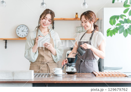 コーヒー教室・珈琲スクールでコーヒーの淹れ方を教える講師の女性と生徒の女性 コーヒー教室・珈琲スクールでコーヒーの淹れ方を教える講師の女性と生徒の女性 129679762