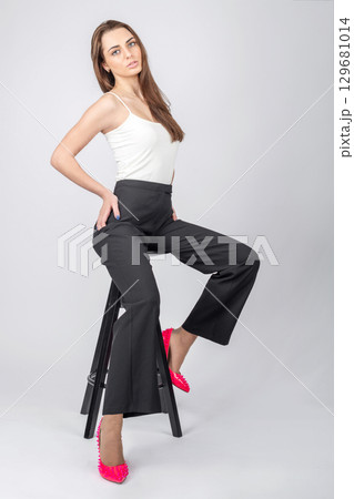 Model sitting on black chair studio fashion portrait Model sitting on black chair studio fashion portrait 129681014