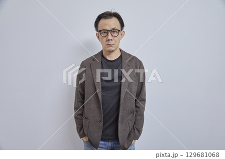 Handsome Asian businessman in suit with eyeglass smile and look at camera on grey background. Handsome Asian businessman in suit with eyeglass smile and look at camera on grey background. 129681068