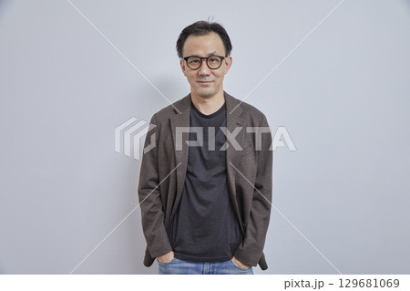 Handsome Asian businessman in suit with eyeglass smile and look at camera on grey background. 129681069