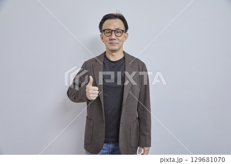Handsome Asian businessman in suit with eyeglass smile and look at camera on grey background. Handsome Asian businessman in suit with eyeglass smile and look at camera on grey background. 129681070