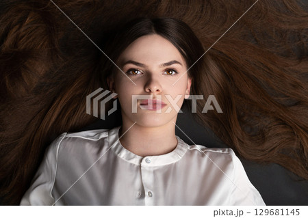 Woman with long brown hair lying on ground Woman with long brown hair lying on ground 129681145