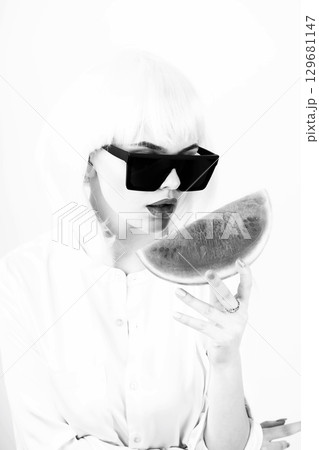 Studio portrait of woman with white wig holding slice of red watermelon 129681147