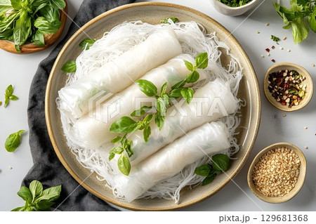 Fresh spring rolls with basil garnish on rice noodles, served on 129681368