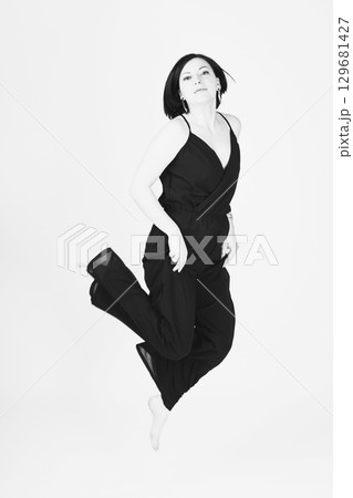 Happy woman with black clothes jumping to air Happy woman with black clothes jumping to air 129681427