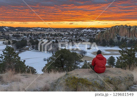 Solitary Figure Contemplates Fiery Sunrise Over Snow-Dusted Land 129681549