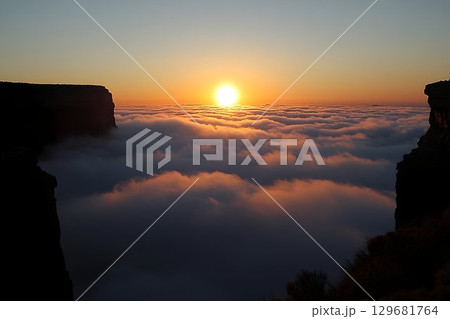 Golden Sunrise Above a Sea of Clouds Framed by Dark Cliffs 129681764
