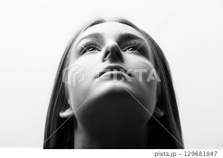 Woman close-up portrait looking up in white studio background Woman close-up portrait looking up in white studio background 129681847