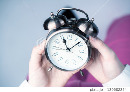 Top view of woman holding retro clock in her hands Top view of woman holding retro clock in her hands 129682234