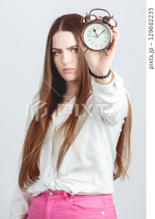 Woman with serious face showing retro clock 129682235