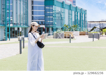 屋外で水分補給をするキャップを被った女性 129682236