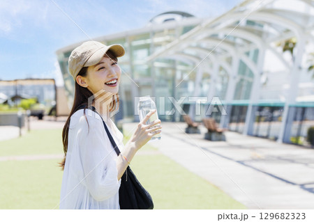 屋外で水分補給をするキャップを被った女性 129682323