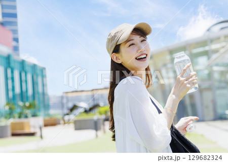 屋外で水分補給をするキャップを被った女性 129682324
