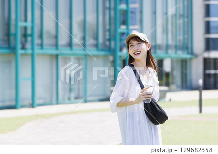 屋外で水分補給をするキャップを被った女性 屋外で水分補給をするキャップを被った女性 129682358
