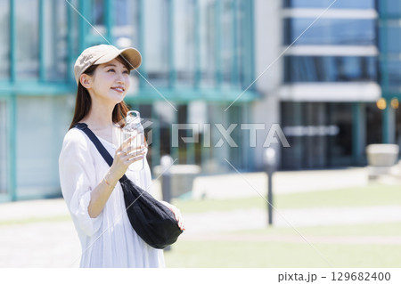 屋外で水分補給をするキャップを被った女性 129682400