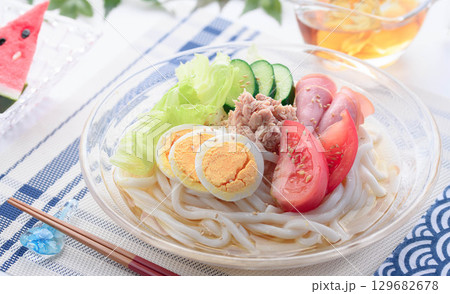 夏にぴったり涼しげなガラス鉢のサラダうどん　野菜と卵とハムを彩りよく盛り付けた冷製麺 129682678