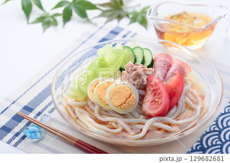 夏にぴったり涼しげなガラス鉢のサラダうどん　野菜と卵とハムを彩りよく盛り付けた冷製麺 129682681