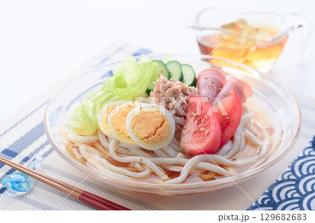 夏にぴったり涼しげなガラス鉢のサラダうどん　野菜と卵とハムを彩りよく盛り付けた冷製麺 129682683