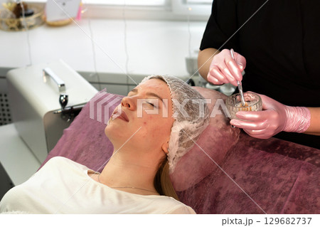 Esthetician mixes organic facial mask ingredients in bowl 129682737