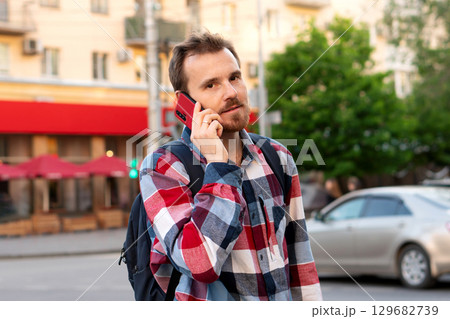 Young man on phone call standing on city street 129682739