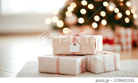 Beautifully wrapped gifts with personalized tags beneath decorated Christmas tree, creating warm and festive atmosphere in New Year winter holiday seasonal celebration 129683291