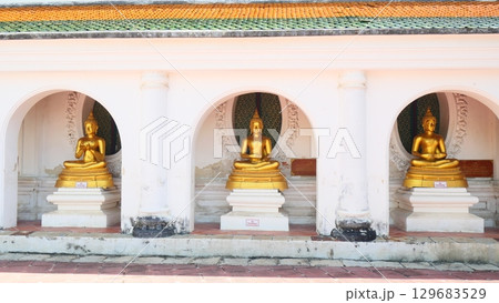 Three golden Buddha statues in a row under arched alcoves at a temple	 129683529