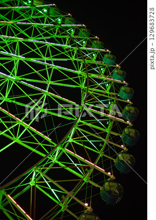 Illuminated green Ferris wheel against dark night sky Illuminated green Ferris wheel against dark night sky 129683728